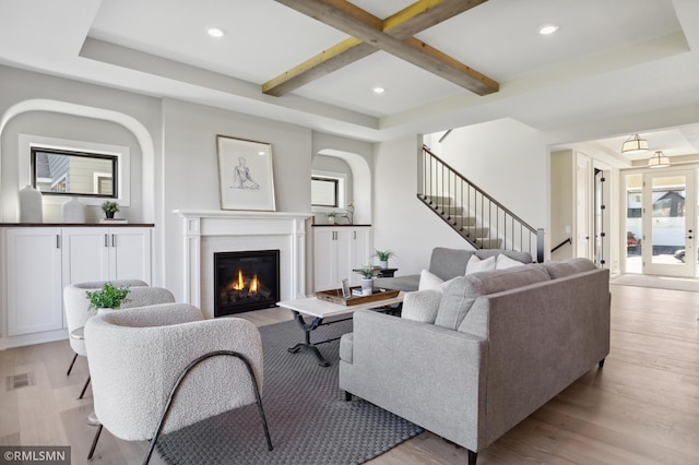 living room featuring beam ceiling and light hardwood / wood-style flooring