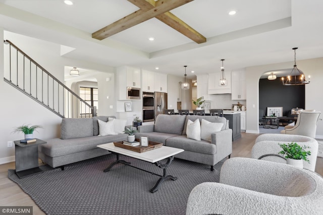 living room featuring beam ceiling, light hardwood / wood-style flooring, and a notable chandelier