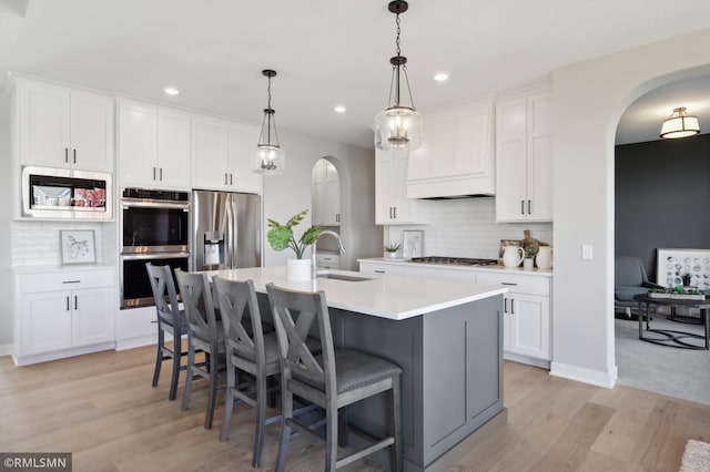 kitchen featuring a center island with sink, white cabinets, and stainless steel appliances