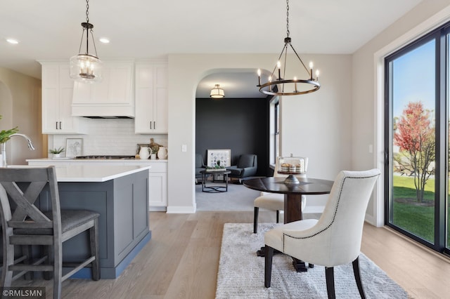 kitchen featuring tasteful backsplash, white cabinetry, hanging light fixtures, and light wood-type flooring