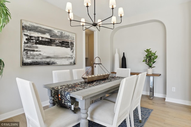 dining area featuring light wood-type flooring and a notable chandelier