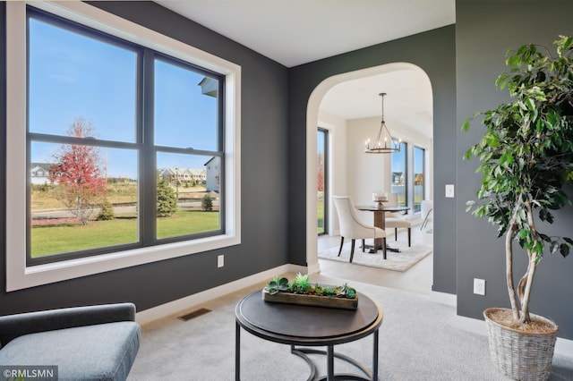 living area featuring carpet floors, a healthy amount of sunlight, and a notable chandelier