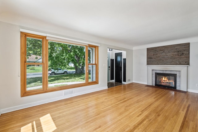 unfurnished living room featuring a healthy amount of sunlight, light hardwood / wood-style flooring, and a fireplace