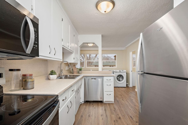 kitchen featuring white cabinetry, sink, washer / clothes dryer, light hardwood / wood-style floors, and appliances with stainless steel finishes