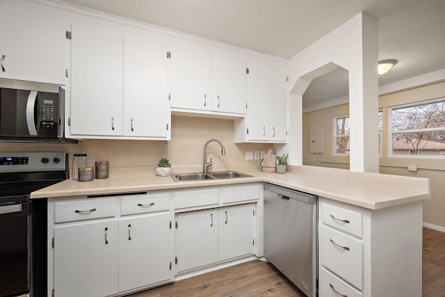 kitchen with kitchen peninsula, sink, white cabinets, and appliances with stainless steel finishes