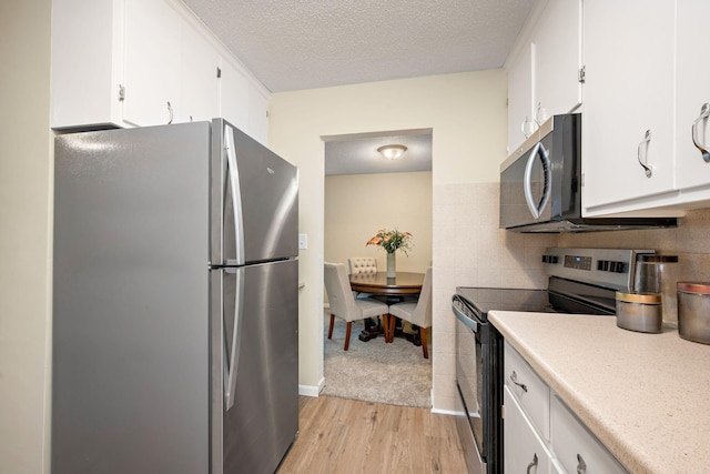 kitchen with a textured ceiling, light wood-type flooring, white cabinetry, and stainless steel appliances