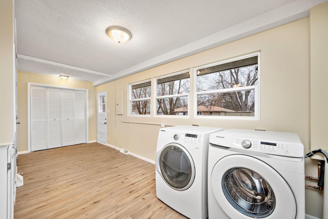 washroom featuring a textured ceiling, separate washer and dryer, and light hardwood / wood-style floors