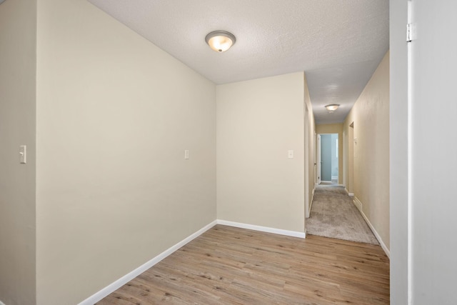 hall with a textured ceiling and light hardwood / wood-style flooring