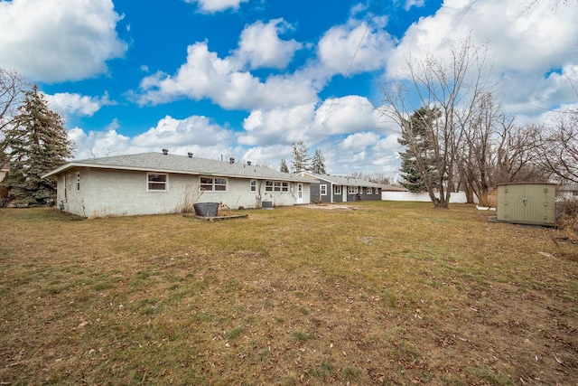 back of property featuring a yard and a storage shed