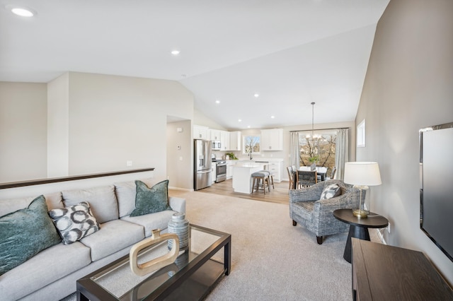 living room with a chandelier, sink, light hardwood / wood-style flooring, and vaulted ceiling