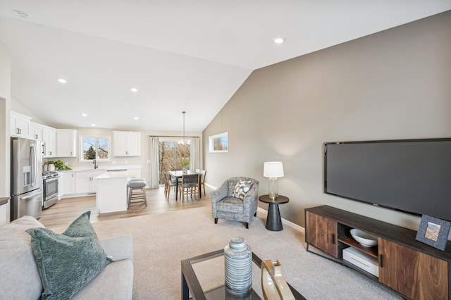 living room with light carpet, vaulted ceiling, and sink