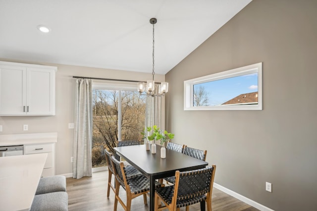 dining space featuring a notable chandelier, lofted ceiling, and light wood-type flooring