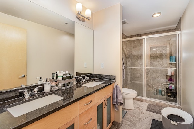 bathroom featuring a shower with door, vanity, and toilet