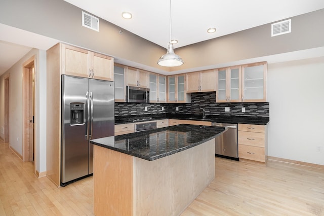 kitchen featuring a center island, light brown cabinets, dark stone countertops, appliances with stainless steel finishes, and backsplash