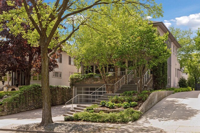 4540 Upton Ave S, Minneapolis, MN 55410 - obstructed view of property with stairway, concrete driveway, a porch, and stucco siding
