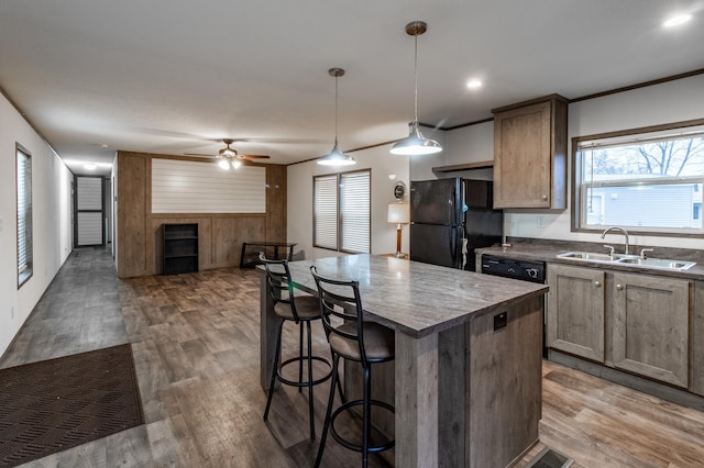 kitchen featuring dark wood-type flooring, sink, black appliances, pendant lighting, and a kitchen island