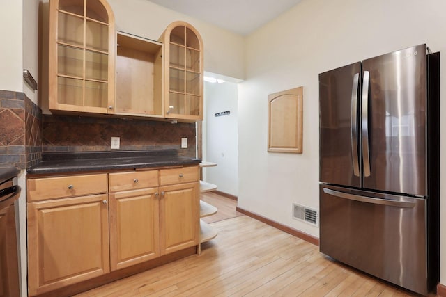 kitchen featuring stainless steel fridge, light wood-type flooring, and backsplash