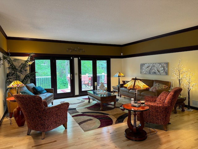 living room featuring a wealth of natural light, light hardwood / wood-style floors, a textured ceiling, and ornamental molding