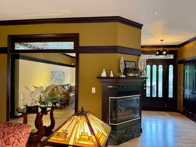 interior space featuring a multi sided fireplace, light hardwood / wood-style floors, crown molding, and a textured ceiling