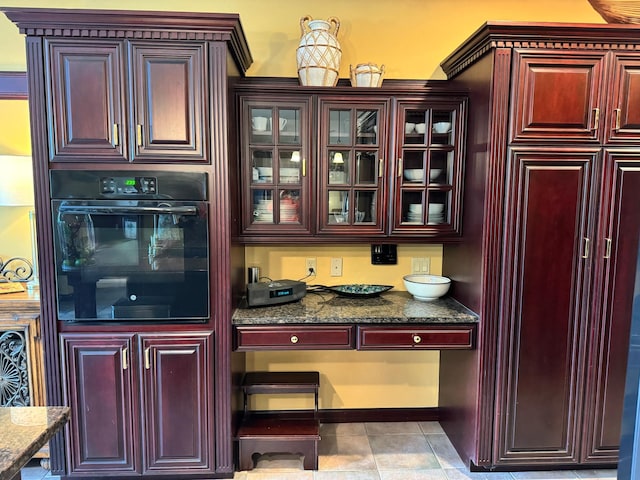 bar featuring black oven, dark stone countertops, and light tile patterned floors