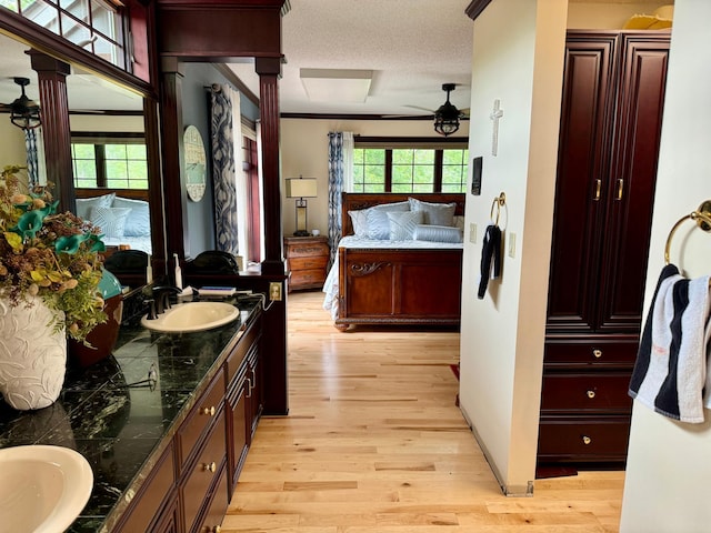 bathroom featuring decorative columns, vanity, a textured ceiling, ceiling fan, and hardwood / wood-style flooring