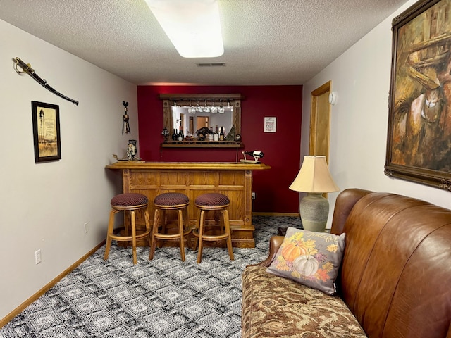 bar featuring carpet floors and a textured ceiling