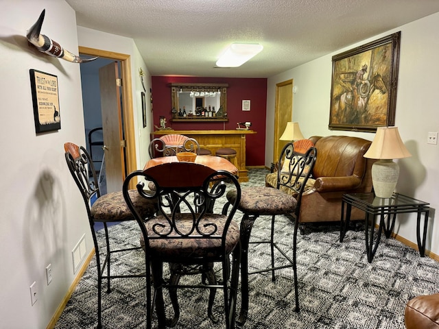 carpeted dining area featuring a textured ceiling