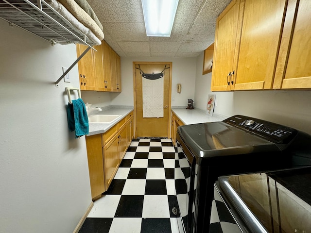 clothes washing area with cabinets, washer and clothes dryer, and sink