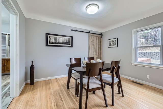 dining room with a barn door and light hardwood / wood-style floors