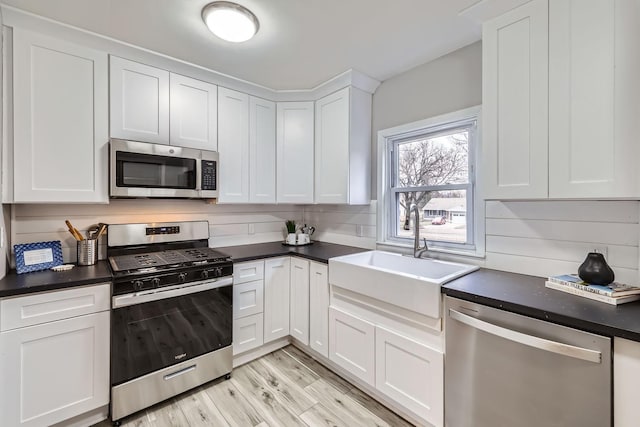 kitchen featuring backsplash, sink, light wood-type flooring, white cabinetry, and stainless steel appliances