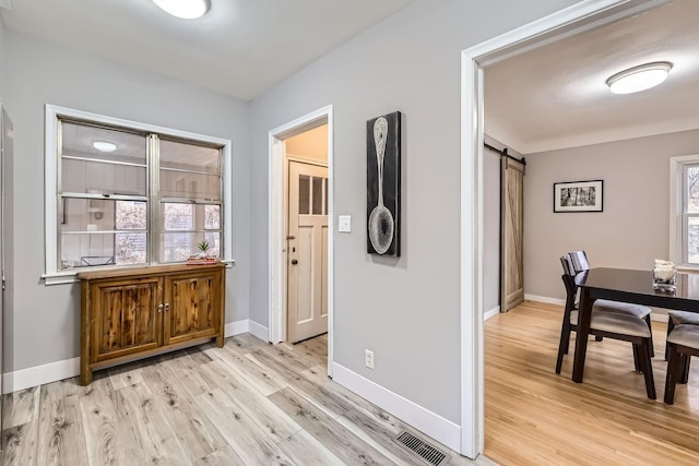 hallway with a barn door and light hardwood / wood-style floors