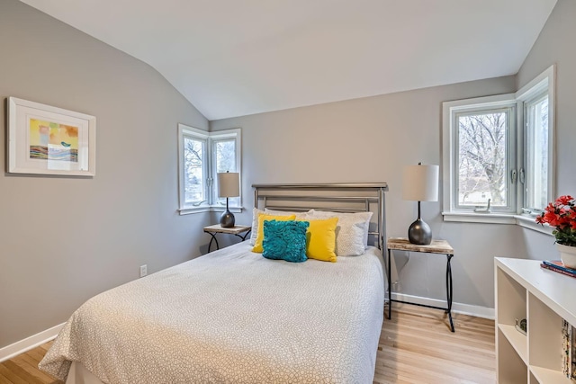 bedroom featuring light hardwood / wood-style floors, multiple windows, and lofted ceiling