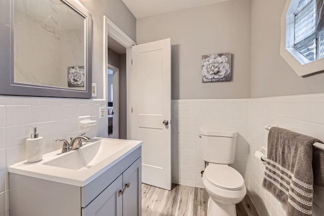 bathroom featuring toilet, vanity, tile walls, and hardwood / wood-style flooring