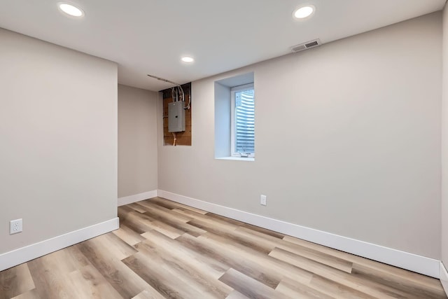 spare room with electric panel and light wood-type flooring