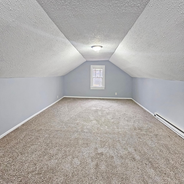 additional living space featuring lofted ceiling, carpet, a textured ceiling, and a baseboard heating unit