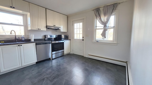 kitchen with appliances with stainless steel finishes, white cabinetry, a baseboard heating unit, and sink