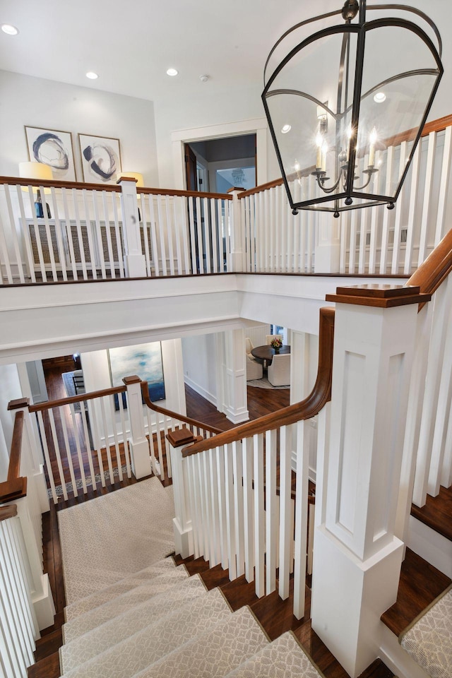 stairs with recessed lighting, wood finished floors, and a chandelier