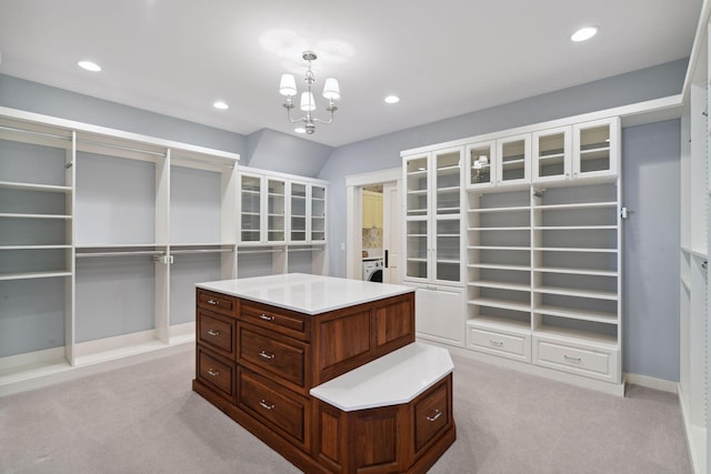 walk in closet featuring light colored carpet, a chandelier, and washer / dryer