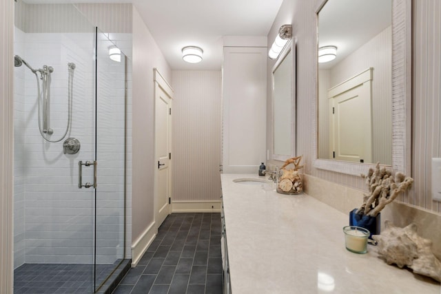 bathroom with a shower stall, vanity, tile patterned flooring, wallpapered walls, and baseboards