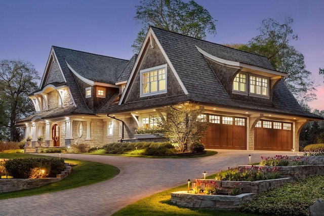 view of front of house featuring curved driveway, an attached garage, and stone siding