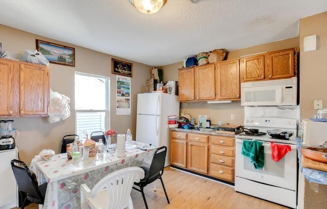 kitchen featuring a textured ceiling, light hardwood / wood-style flooring, and white appliances