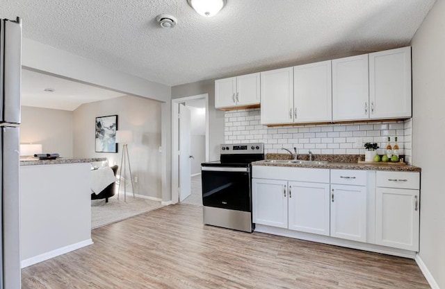 kitchen with electric stove, white cabinetry, sink, and light hardwood / wood-style floors