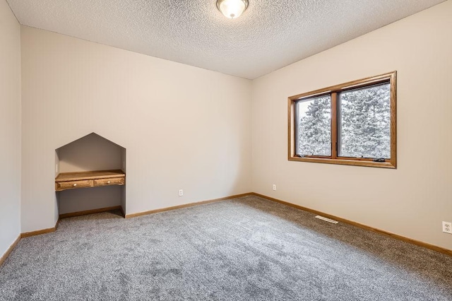 carpeted empty room with a textured ceiling