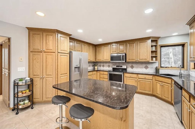 kitchen featuring a breakfast bar, sink, light tile patterned floors, stainless steel appliances, and backsplash