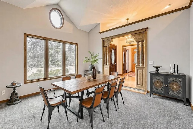 carpeted dining area featuring lofted ceiling, a notable chandelier, and decorative columns