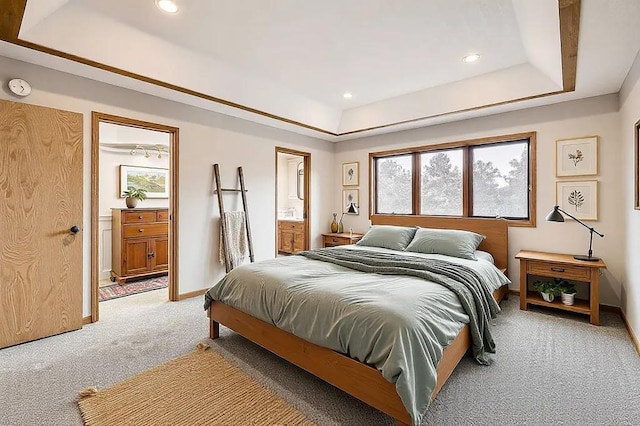 carpeted bedroom with ensuite bathroom and a raised ceiling