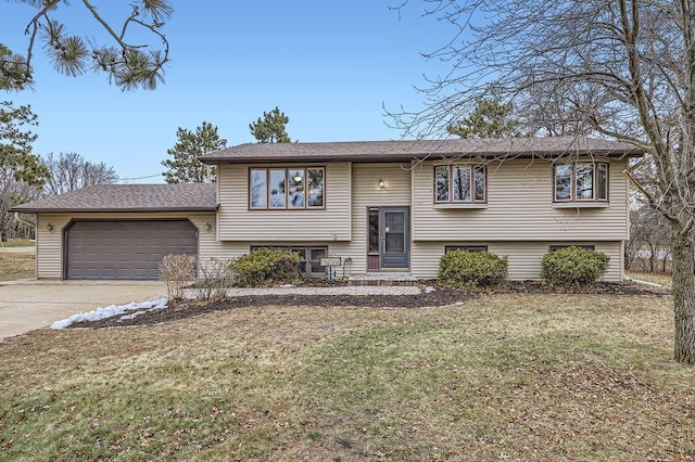 raised ranch featuring a garage and a front lawn