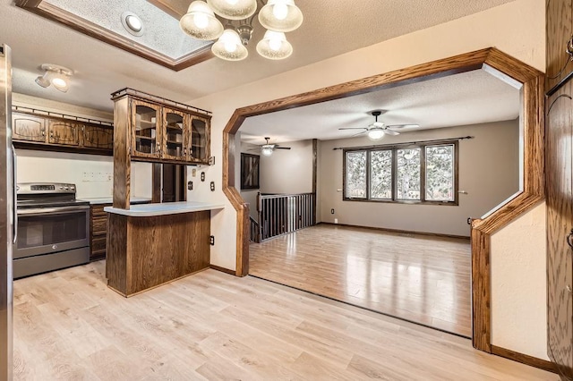 kitchen featuring stainless steel electric range oven, kitchen peninsula, dark brown cabinets, a textured ceiling, and light hardwood / wood-style flooring