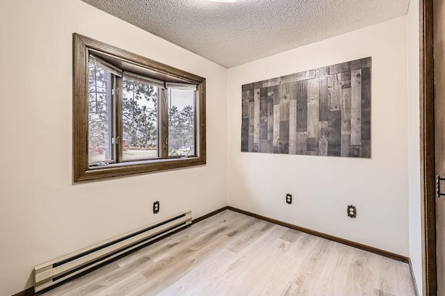 spare room featuring light hardwood / wood-style flooring, a textured ceiling, and baseboard heating