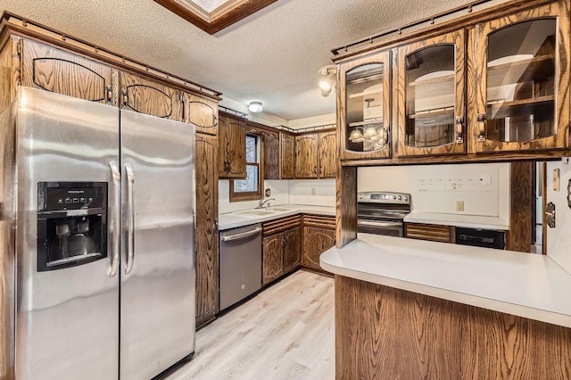 kitchen featuring sink, stainless steel appliances, light hardwood / wood-style floors, a textured ceiling, and kitchen peninsula